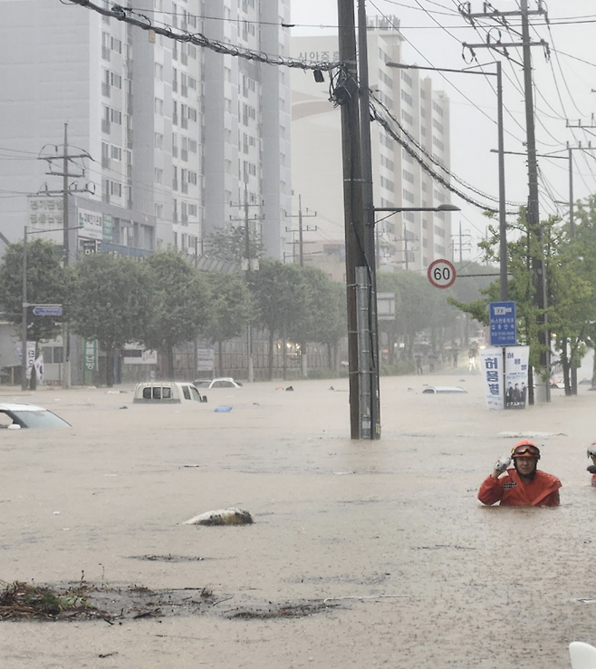 차량들만 둥둥 떠다닌다. 18일 오후 광주 북구 신안동 한 도로가 폭우로 완전히 잠겨 구조대원이 허리까지 찬 물을 헤치며 수색에 나서고 있다. 엑스 갈무리