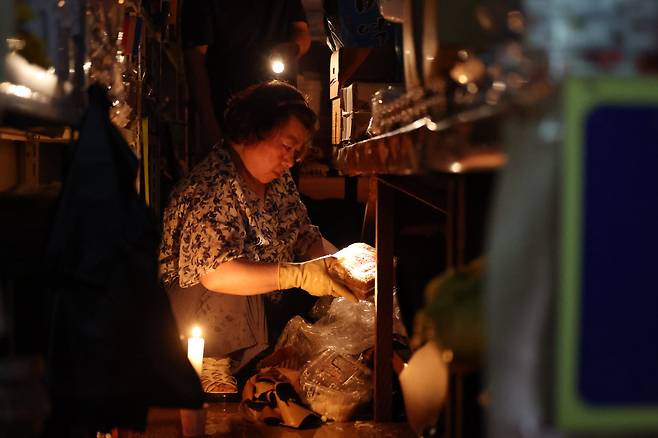 충청 지역에 기록적인 폭우가 쏟아진 가운데 지난 17일 충남 당진전통시장에서 한 상인이 전기가 나가자 촛불을 켜고 수해의 흔적을 복구하고 있다. /장경식 기자