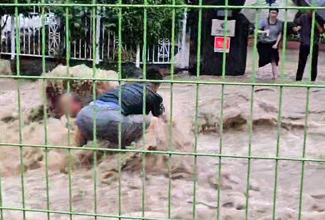 지난 17일 광주광역시 동구 소태동에서 최승일(54)씨가 폭우 속 맨홀에 빠진 노인을 구하고 있다. /연합뉴스