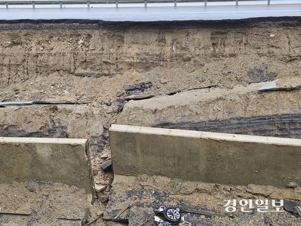 지난 16일 오후 7시께 오산 가장동 서부우회도로의 고가도로 옹벽이 무너지면서 1명이 사망했다. 밤새 내린 비로 복구작업이 중단된 17일 오전, 무너진 옹벽 흙더미 속에 전날 사고의 잔해가 어지럽게 흩어져있다. 2025.7.17 오산/공지영기자 jyg@kyeongin.com