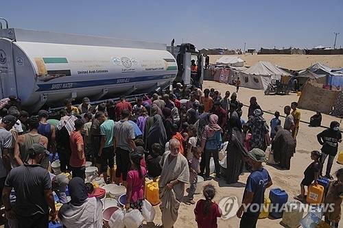 지난 19일(현지시간) 가자지구 남부 칸유니스 구호소 물탱크 트럭 앞에 물을 받으려고 모인 팔레스타인 주민들. AP=연합뉴스
