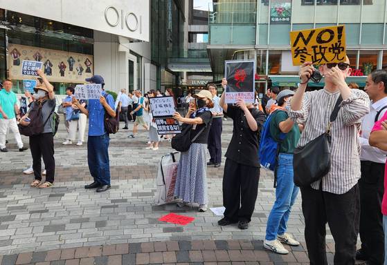 지난 17일 도쿄에서 참정당 후보자 유세장 뒤에 일부 시민들이 반대하는 피켓을 들고 있다. 오누키 도모코 특파원