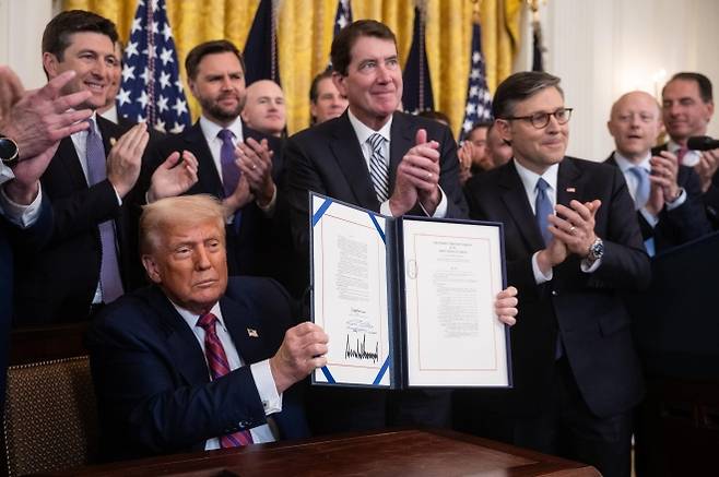 트럼프 ‘지니어스 법’ 서명 - 도널드 트럼프 미국 대통령이 JD 밴스(뒷줄 왼쪽 두 번째부터) 부통령, 빌 해거티 공화당 상원의원, 마이크 존슨 하원의장 등이 박수 치는 가운데 스테이블코인 규제 틀을 규정한 ‘지니어스 법’에 서명한 뒤 문서를 들어 보이고 있다. 워싱턴DC EPA 연합뉴스