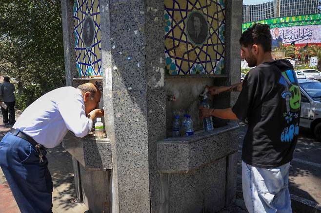 22일(현지시간) 이란 테헤란에서 폭염으로 인해 기온이 급상승한 가운데 이란인들이 공공 거리 분수대에서 물을 마시고 있다.(사진=AFP)
