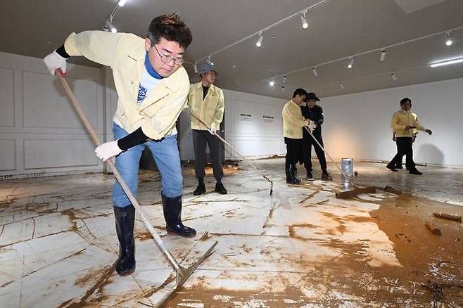 박찬대 더불어민주당 당대표 후보가 21일 오후 광주 서구 한 수해 피해 가구백화점을 찾아 수해복구 봉사활동에 참여하며 밀대를 이용해 흙탕물을 정리하고 있다. ⓒ뉴시스