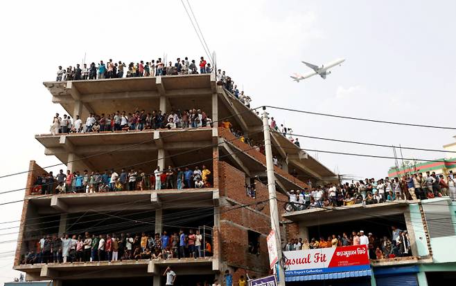 방글라데시에서 공군 훈련기가 이륙직후 기술적 오작동을 일으켜 학교 건물에 추락해 약 200명의 사상자가 발생했다. 사진은 21일(현지시각) 방글라데시 다카의 마일스톤 칼리지 캠퍼스에 공군 훈련용 항공기가 추락한 후 구경꾼들이 구조 작업을 지켜보는 가운데 여객기가 날아가고 있는 모습. /사진=로이터