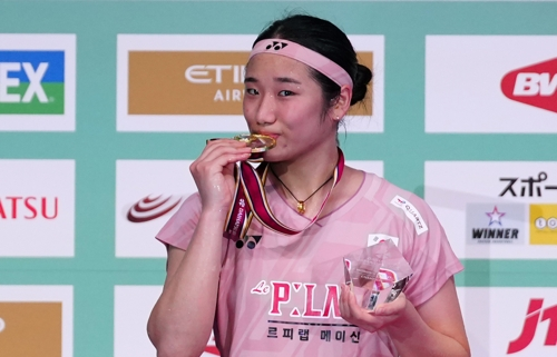 안세영이 20일 일본오픈 결승에서 왕즈이를 꺾고 우승한 뒤 금메달을 깨물고 있다. 신화연합뉴스