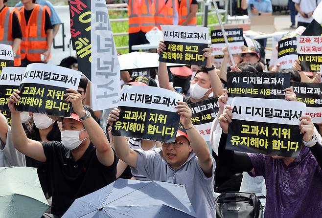 한국교과서협회 회원들이 지난 21일 오전 서울 영등포구 여의도 국회의사당역 앞에서 열린 초·중등교육법 개정안 규탄 집회에서 AI 디지털교과서(AIDT)의 '교과서' 지위 유지를 촉구하고 있다. 뉴스1