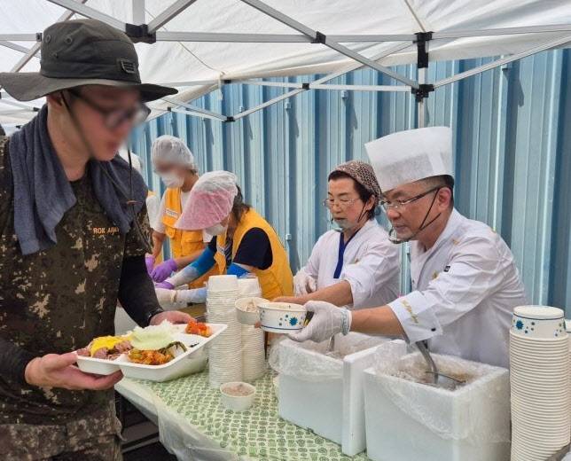 24일 침수 피해 복구가 한창인 나주시 동강면 대지리 일대에서 '흑백요리사'로 알려진 안유성 셰프가 군 장병에게 식사를 전달하고 있다.(사진=뉴스1, 대한적십자사 제공)