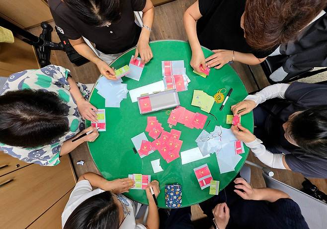 지난 24일 광주 북구 용봉동 행정복지센터에서 직원과 통장들이 민생회복 소비쿠폰 현물카드에 스티커를 붙여 색상을 교체하고 있다. /광주 북구