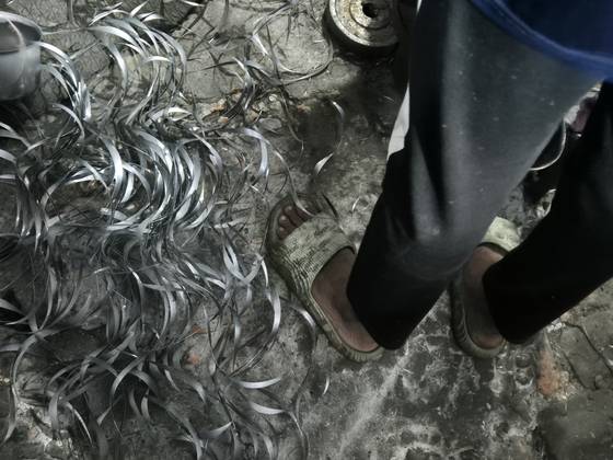 공장 바닥엔 연마 과정에서 잘라낸 날카로운 알루미늄 조각이 빼곡하게 깔려 있지만 모하마드는 맨발에 슬리퍼만 신은 채 일하고 있다. 다카=전율 기자