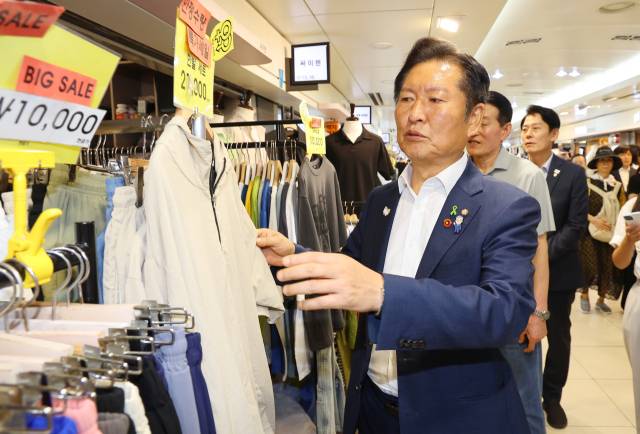 정청래 더불어민주당 당대표 후보가 30일 인천 부평구 부평역지하상가에서 상인들과 인사를 나눈 후 진열된 옷을 살펴보고 있다. 연합뉴스