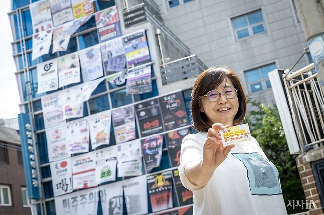 깃발 프린트로 뒤덮인 식민지역사박물관 앞에서 ‘민주주의와 깃발’ 전시 작업을 총괄한 김승은 학예실장이 7월15일 ‘당신의 민주주의를 기증받습니다’ 명함을 내밀고 있다. ⓒ시사IN 박미소