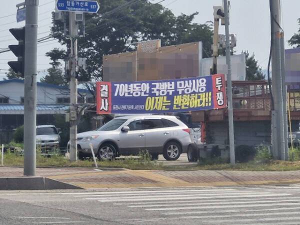 포천시의 한 거리에 정부의 군 유휴지 반환을 요구하는 플래카드가 걸린 모습. 휴전 이후 정부는 개인 소유였던 땅들을 강제 매입해 군사 기지로 사용했으나, 군사기지 이전 및 통폐합으로 방치된 군 유휴지들에 대한 매각 및 반환 계획이 뚜렷이 없어 시민들이 지속적으로 반환을 요구하고 있다. 박채령기자