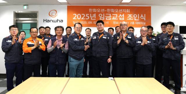 한화오션 김희철 대표이사(앞줄 왼쪽에서 네번째)와 전국금속노조 경남지부 한화오션지회 김유철 지회장(앞줄 왼쪽에서 다섯번째) 등 노사 교섭위원들이 임금 교섭 조인식을 마친 후 기념촬영을 하고 있다. 한화오션 제공