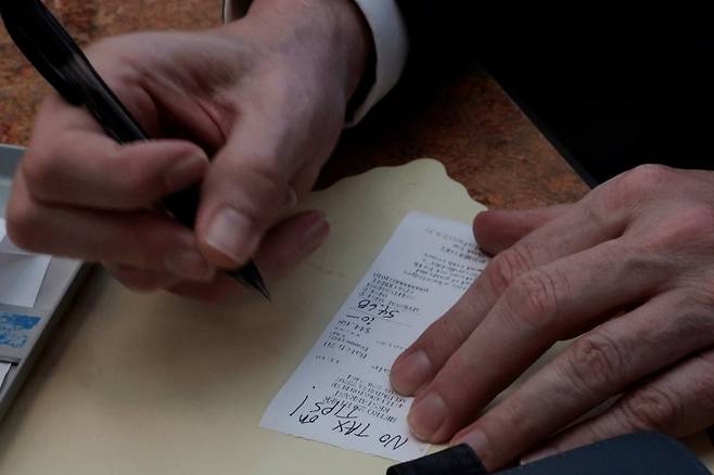 스콧 베선트 미국 재무장관이 1일(현지시간) 버지니아 알링턴의 한 식당을 찾아 식사한 후 영수증에 '팁에는 비과세'라는 트럼프 정부 정책을 홍보하는 문구를 남기고 있다. /로이터연합뉴스