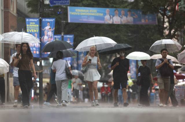 지난달 비가 내리는 서울 명동 거리에 외국인 관광객들이 우산을 쓴 채 걸어가고 있다. 연합뉴스