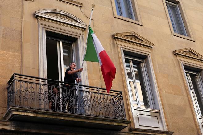 패션 분야 세계적 거장 조르지오 아르마니(이탈리아)가 91세로 세상을 떠났다. 사진은 지난 4일(현지시각) 이탈리아 밀라노에서 패션 디자이너 조르지오 아르마니의 별세 소식을 접한 한 시민이 이탈리아 국기를 조기 게양하며 애도를 표하는 모습. /사진=로이터