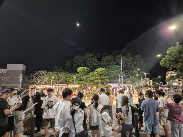 6일 밤 부산 해운대구 송정해수욕장에서 열린 송정 별바다 과학축제를 찾은 관광객들이 죽도공원 위에 뜬 보름달을 관측하기 위해 천체망원경 쪽으로 몰려 차례를 기다리고 있다. 부산과학기술협의회 제공