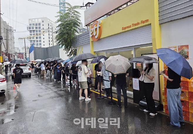 폭우 속에서도 서울 성수동 ETF 베이커리 앞에 줄을 선 방문객들. 경제 유튜버 슈카월드가 만든 빵을 사기 위해 아침부터 대기행렬이 이어졌다. (사진=한전진 기자)