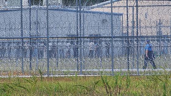 현지시간 6일 미국 조지아주 포크스턴에 위치한 불법 체류자 구금 시설에 수감된 한국인 근로자들이 추가 조사를 받기 위해 줄을 서서 이동하고 있다. 이들은 푸른색 수용복 차림으로 손에는 서류를 들고 있었다. 이들 앞에 제복을 입은 시설 관계자가 근로자들을 통제하고 있는 모습니 보인다. 포크스턴=강태화 특파원