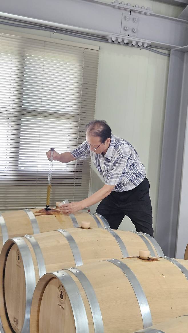 오크통에서 숙성 중인 증류식 소주의 원액을 채취 중인 오세용 대표.