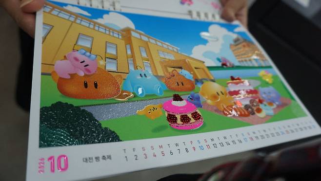 동인피오디가 '아시아 프린트 어워드 2025'에서 수상한 '대전시 공식 마스코트와 함께하는 2026년 달력(꿈씨패밀리 탁상형 캘린더)'. 해당 캘린더는 꿈씨패밀리가 월별로 대전의 명소를 탐방하는 스토리로 구성됐으며, 에폭시를 활용한 높낮이 구현과 3D 디지털 포일(박)을 통해 완성도를 높여 호평을 받았다. /김흥수 기자