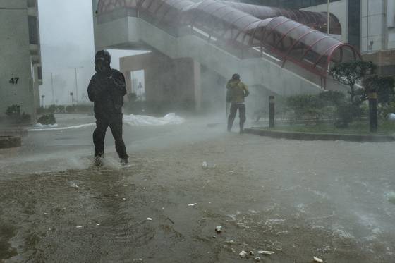 초강력 태풍 ‘라가사’가 상륙한 24일(현지시간) 홍콩 헝파추엔 지역에서 주민들이 침수된 거리를 지나고 있다. AP=연합뉴스