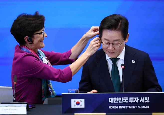 이재명 대통령, 뉴욕에서 한국경제설명회 - 이재명 대통령이 25일(현지시간) 미국 뉴욕 증권거래소에서 열린 한국경제설명회 투자서밋에서 제인 프레이저 씨티그룹 회장의 도움을 받아 번통역기를 착용하고 있다. 뉴욕 연합뉴스