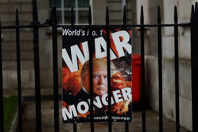 아일랜드 더블린의 한 철책에 27일(현지시간) 도널드 트럼프 미국 대통령을 ‘전쟁광’이라고 비난하는 포스터가 붙어 있다. 로이터연합뉴스