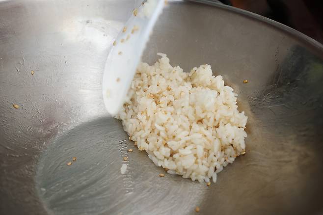 주휘씨가 소금, 참기름, 깨로 간을 한 밥을 주걱으로 섞고 있다.