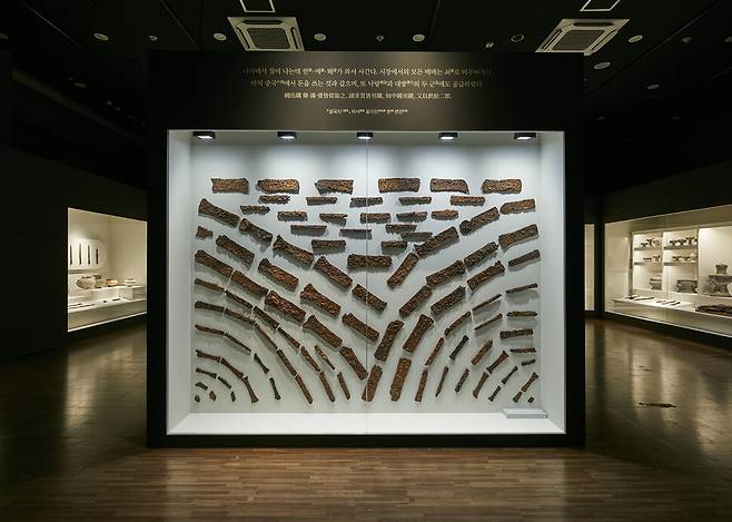 국립김해박물관의 특별전 ‘시간의 공존: 김해 대성동 고분군’ 1부 전시장 들머리에서 관객을 맞는 덩이쇠들. ‘철의 나라’ 가야를 상징하는 유물들을 세워진 벽에 물결 모양으로 색다르게 배치해 놓았다. 국립김해박물관 제공