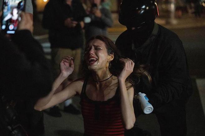 한 시위자가 2일(현지시각) 미국 오리건주 포틀랜드의 이민세관단속국(ICE) 구금시설 앞에서 열린 이민정책에 반대하는 시위 중 국토안보부 직원들이 뿌린 스프레이에 괴로워하고 있다. 도널드 트럼프 미국 대통령은 오리건주 포틀랜드에 군 병력을 배치하고 필요시 전면 무력 사용을 지시한 바 있다. 포틀랜드/AP 연합뉴스