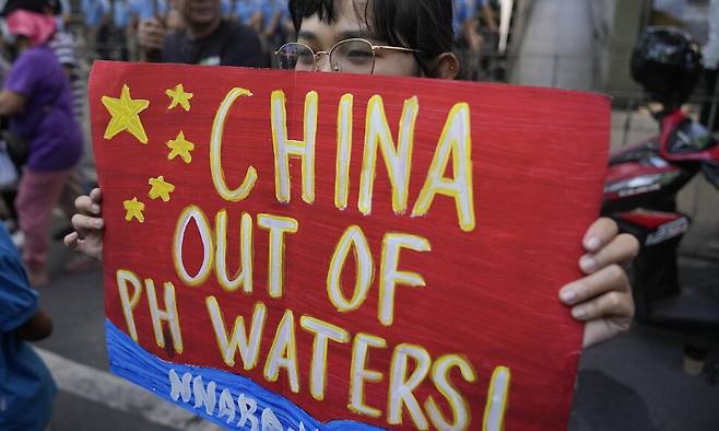 2024년 2월6일(현지시각) 필리핀 메트로 마닐라의 마카티 중국영사관 앞에서 시민이 “중국은 필리핀 영해를 떠나라”라고 쓴 중국 국기 문양의 포스터를 들고 서 있다. AP 연합뉴스