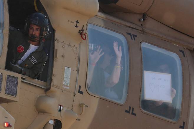 13일(현지시간) 팔레스타인 무장세력 하마스에 2023년 10월 납치됐다가 2년 만에 석방된 이스라엘 인질들이 본국으로 귀환하는 헬기 안에서 메모를 들고 있는 모습./로이터=뉴스1