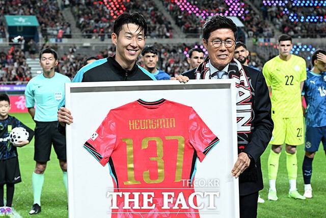한국 남자 선수 A매치 최다 출전 달성에 성공한 손흥민(왼쪽)이 14일 오후 서울 마포구 서울월드컵경기장에서 열린 'Legend Old & New – From Cha, To. Son' 특별 행사에서 차범근 전 감독에게 기념 유니폼을 전달 받은 뒤 기념촬영을 하고 있다. /서울월드컵경기장=남용희 기자