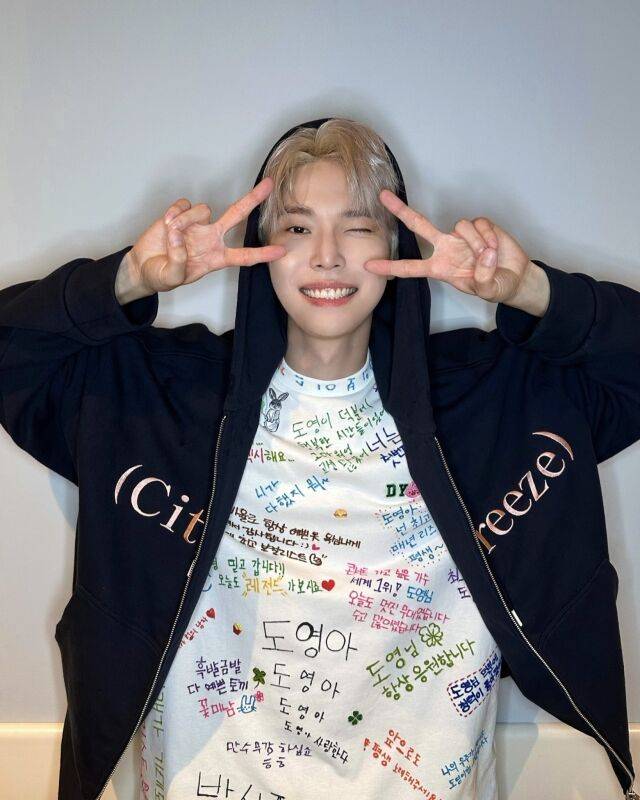 스태프들의 응원 문구가 적힌 티셔츠를 입은 도영이 밝게 미소 짓고 있다. / NCT 인스타그램