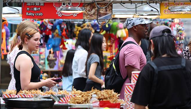 시장에서 한국인들의 먹거리를 즐기는 외국인 관광객. 연합뉴스