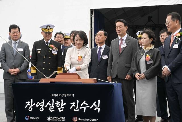 22일 한화오션 거제 사업장에서 열린 장보고‑Ⅲ 배치‑Ⅱ 1번함 장영실함 진수식에서 강동길 해군참모총장의 부인 박미영(왼쪽 3번째) 여사가 장영실함에 연결된 진수줄을 절단하고 있다. 해군 제공