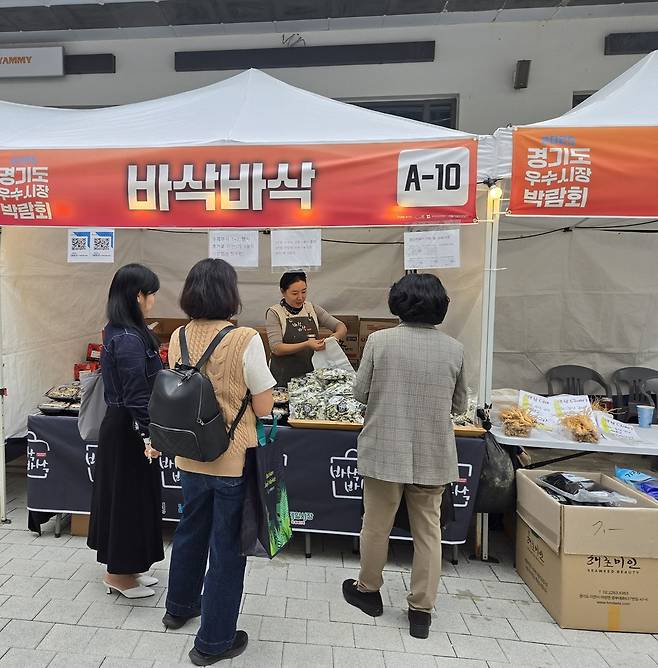 지난 24~25일 시흥시 거북섬 보니타가 광장에서 열린 '2025 경기도 우수시장 박람회'의 부천제일시장 '바삭바삭' 부스에서 방문객들이 상품을 구매하고 있다. <정경아 기자>