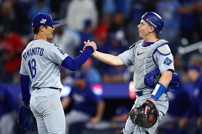 LA 다저스 윌 스미스(오른쪽)가 26일 토론토와의 월드시리즈 2차전에서 완투한 야마모토 요시노부와 악수를 나누고 있다. Getty Images코리아