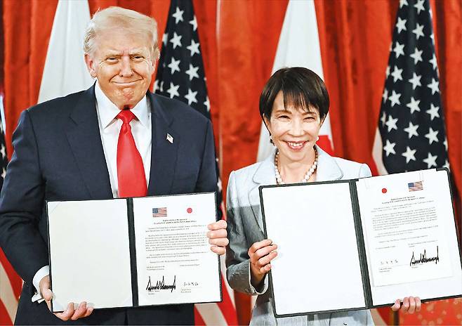 28일 일본 도쿄 영빈관에서 정상회담을 가진 도널드 트럼프(왼쪽) 미국 대통령과 다카이치 사나에 일본 총리가 ‘미·일 동맹의 새로운 황금기를 향하여’라는 문서에 서명한 뒤 취재진에게 들어 보이고 있다. / AFP 연합뉴스