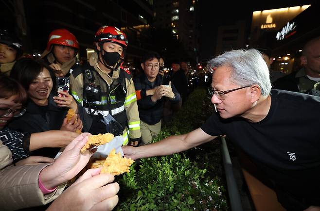 젠슨 황 엔비디아 최고경영자가 30일 서울 삼성동 한 치킨집에서 진행된 이재용 삼성전자 회장, 정의선 현대차그룹 회장과 치맥 회동 중 시민에게 치킨과 감자튀김을 나눠주고 있다. 공동취재사진