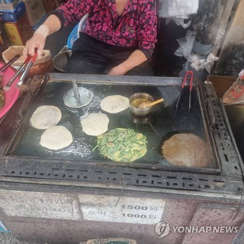 분주한 호떡 굽기 (서울=연합뉴스) 서윤호 인턴기자 = 지난 30일 서울 동작구 흑석시장 초입의 한 가게에서 부추전과 호떡을 팔고 있다. 2025.10.31