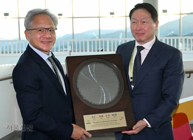 젠슨 황(왼쪽) 엔비디아 최고경영자(CEO)가 지난달 31일 ‘아시아태평양경제협력체(APEC) 최고경영자(CEO) 서밋’ 특별 연설 후 경북 경주시 경주예술의전당 복도에서 최태원 대한상공회의소 회장 겸 SK그룹 회장과 함께 SK하이닉스 반도체 웨이퍼가 담긴 기념패를 들고 있다. 경주 홍윤기 기자
