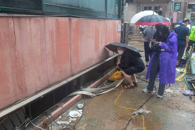 2022년 8월8일 밤 내린 폭우로 고립돼 3명이 숨진 서울 관악구 신림동 빌라 반지하 가구 창문 앞에서 2022년 8월9일 보도진과 이웃 주민들이 주변을 살피고 있다. 한겨레 자료