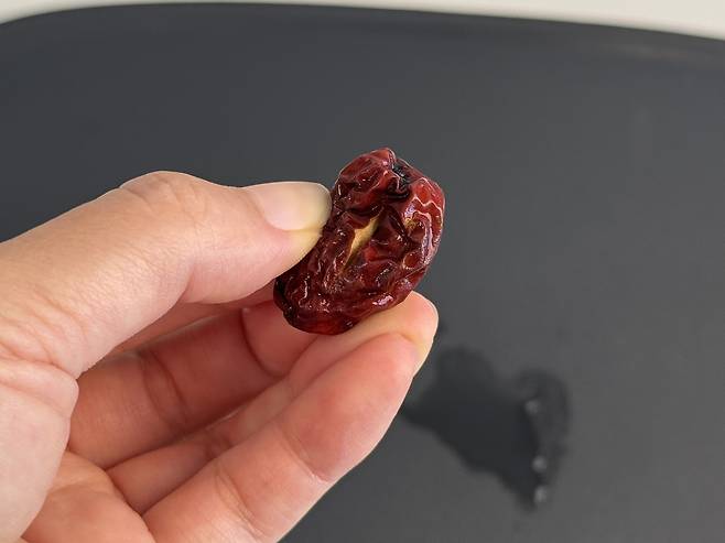 칼집이 난 대추 한개를 들고있는 손