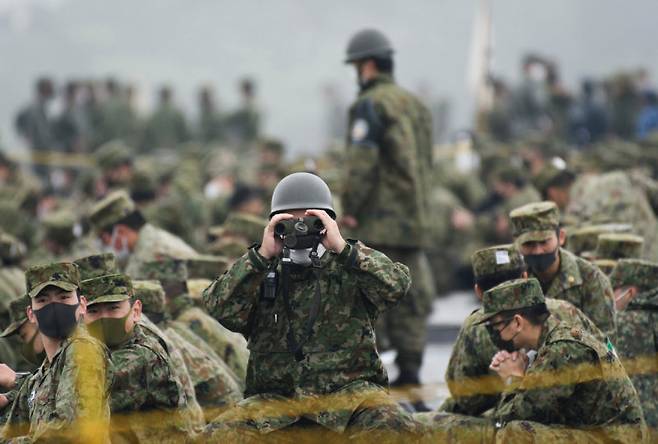 일본 정부가 자위대 창설 71년 만에 계급 명칭을 외국 군대와 동일한 체계로 개편하는 방안을 검토하고 있다고 13일 밝혔다. ‘방어’만 가능한 자위대를 외국 정규군과 같은 체제로 만들려는 것 아니냐는 분석이 나온다. 한 자위대원이 2021년 5월 도쿄 인근 시즈오카현 고텐바의 훈련장에서 쌍안경을 들여다보고 있다. 고텐바=AP 뉴시스