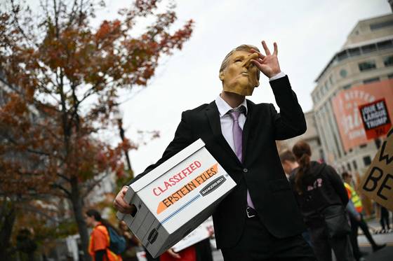 15일(현지시간) 워싱턴 DC 백악관 앞에서 한 시위자가 피노키오 코가 달린 도널드 트럼프 미국 대통령 마스크를 쓰고 '기밀 엡스타인 파일'이라고 적힌 상자를 들고 있다. AFP=연합뉴스