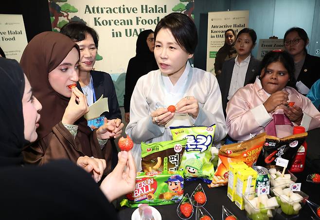 이재명 대통령과 아랍에미리트(UAE)를 국빈 방문 중인 김혜경 여사가 19일(현지시각) 아부다비 주아랍에미리트 한국문화원에서 열린 ‘할랄 케이(K)푸드’ 홍보 행사에서 참석자들과 한국 과자를 맛보고 있다. 연합뉴스